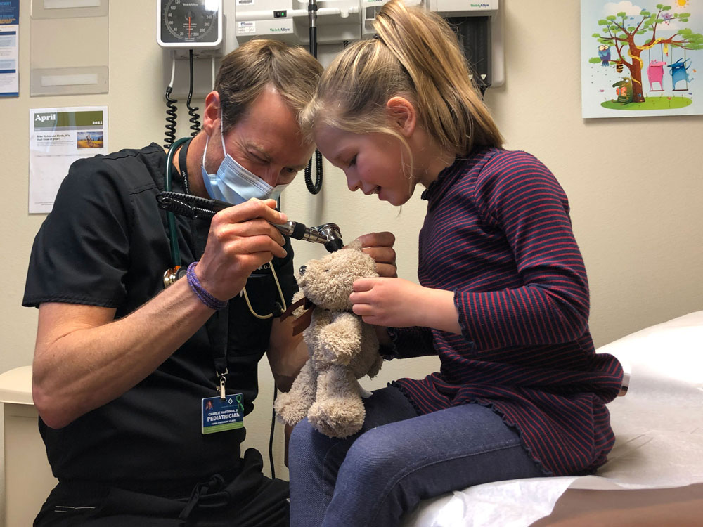 nurse and child with a stuffed bear